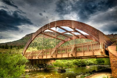 The wooden arch of the Apple Valley Road bridge over the North St. Vrain, with the hogback behind
