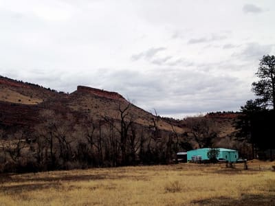 A meadow at dusk with the hogback behind and a turquoise cabin