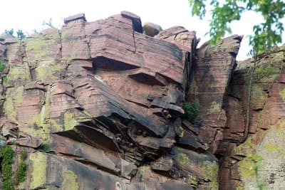 Layered red sandstone cliff face above trees at the Planet Bluegrass ranch
